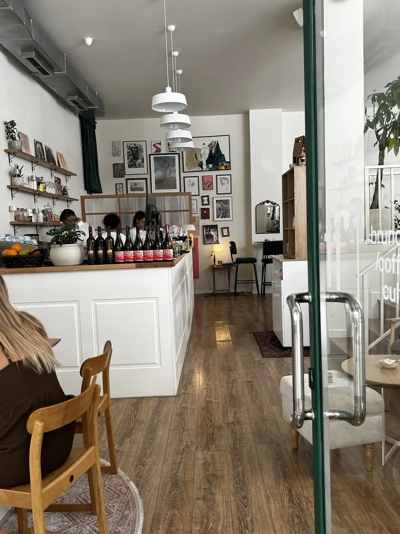The coffee bar of 11 with framed prints, plants and wine bottles