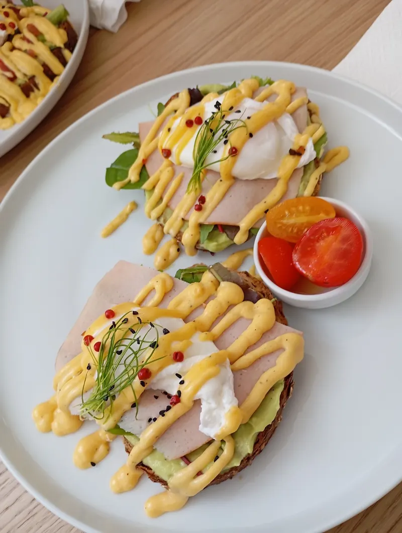 Toast with ham, poached eggs and sauce, with cherry tomatoes