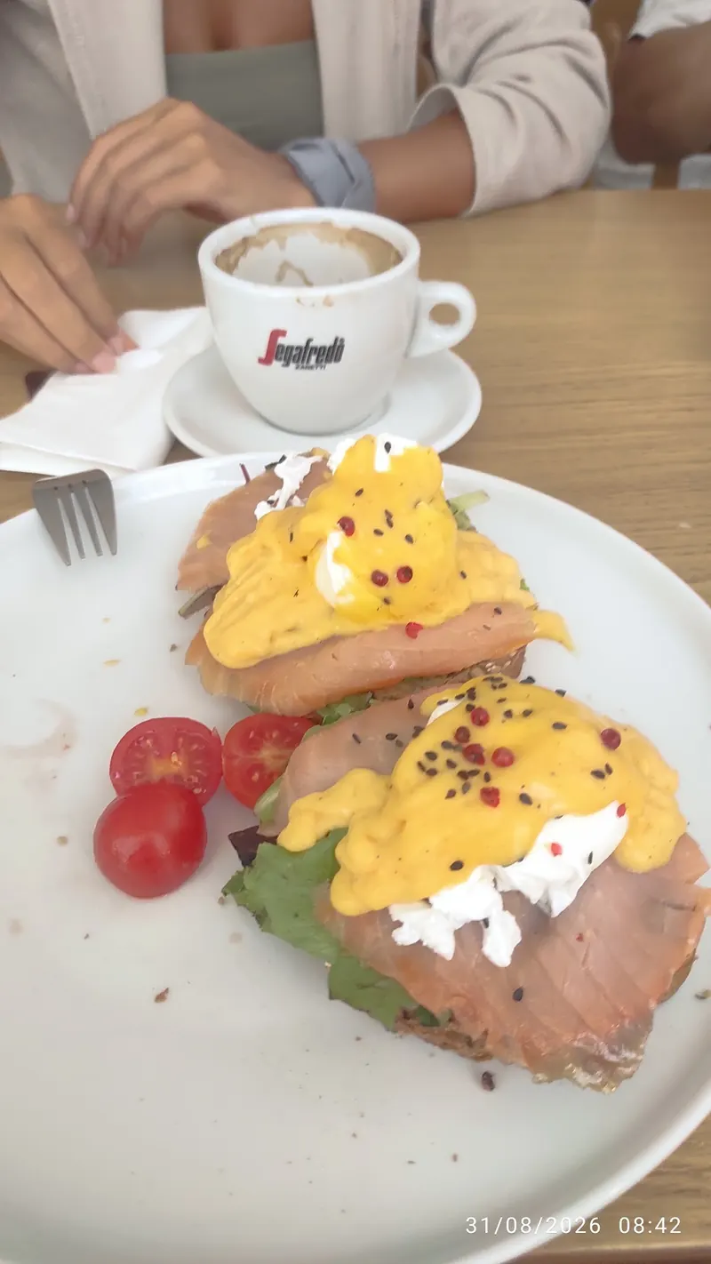 Eggs Benedict with salmon, next to a cappuccino